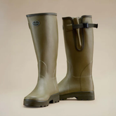 Pair of green rubber boots on a beige background